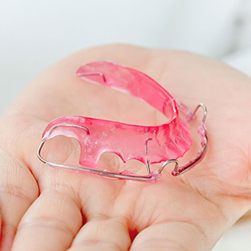 orthodontist holding retainer in Brampton