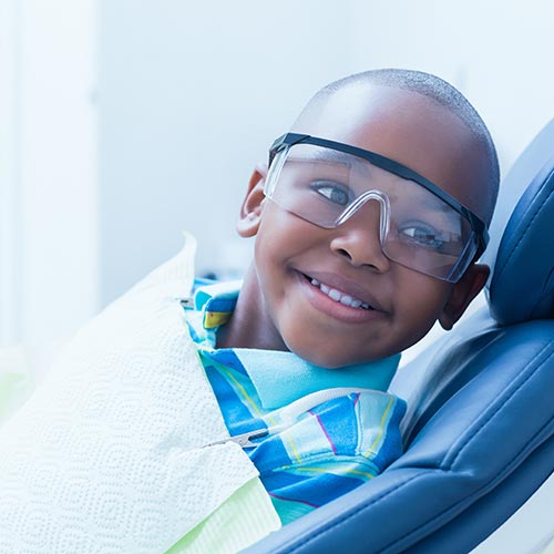 smiling boy waiting for dental exam by a pediatric dentist in Brampton